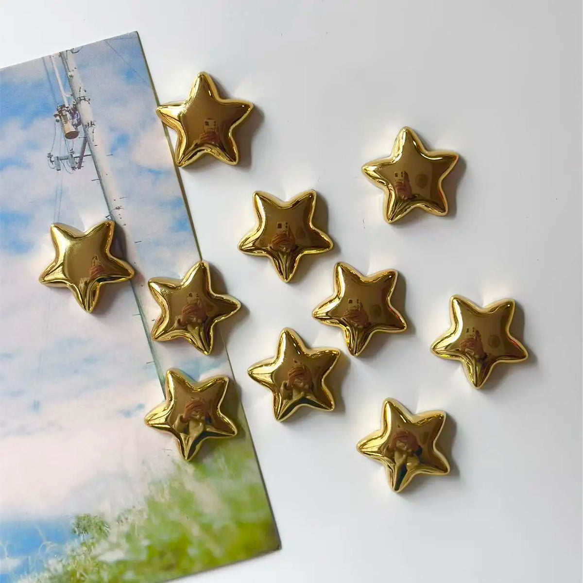 A set of gold star-shaped fridge magnets displayed on a light blue and green background.