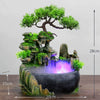 A resin waterfall desktop fountain featuring a mossy rock structure and illuminated water flow.