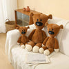 A brown teddy bear stuffed plush toy sitting on a white blanket next to a wooden box.