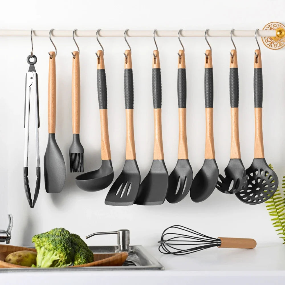 A set of ten S-shape stainless steel hanging kitchen utensils, including spatulas and forks, are displayed on a white shelf.