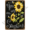 A dark metal sign with white script and yellow sunflower illustrations, featuring the text You are my Sunshine.