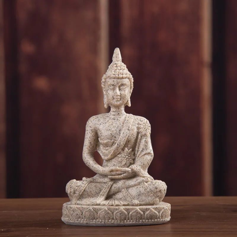 A handcrafted resin Buddha statue figurine seated in meditation on a wooden surface.