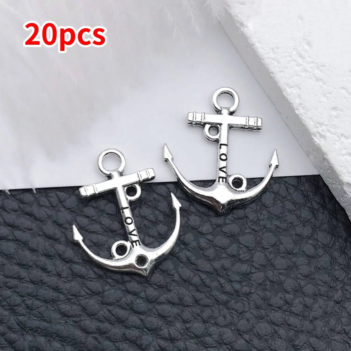 20 pieces of silver vintage ship anchor charms for jewelry making displayed on a dark surface.