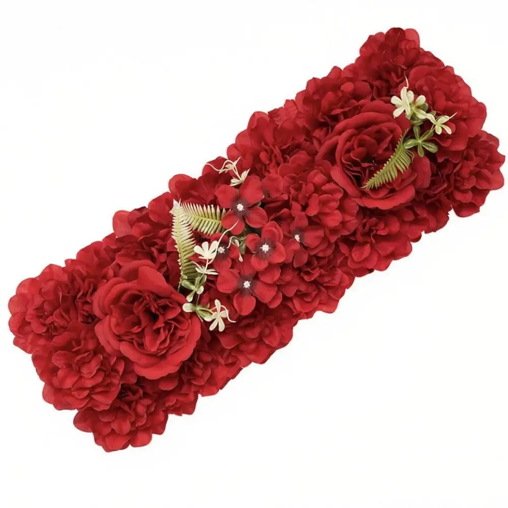 A dense, long arrangement of deep red artificial roses and greenery used for wedding and party decor.