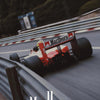 A blurred image of a red and white Marlboro Formula 1 car on a track, with the word Marlboro visible in the foreground.