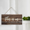 Rustic wooden wall sign with white script text that reads This is us our life our story our home