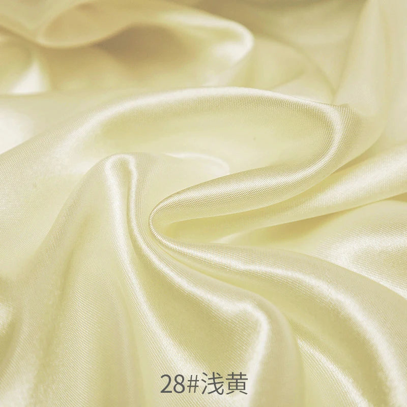 Cream satin fabric draped in soft folds for sewing and DIY projects