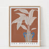 Wall art featuring a potted philodendron plant in a blue ceramic vase against a terracotta background.
