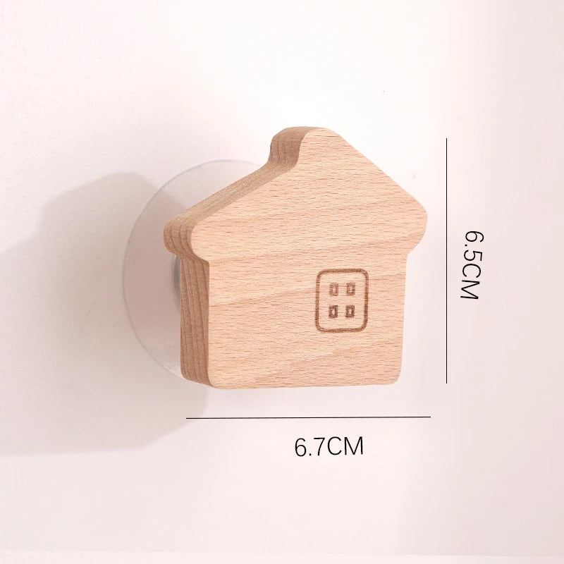 A small wooden house shaped hook with a window, made of light wood.