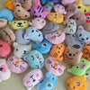 A collection of small, soft plush dolls shaped like cats in various pastel and earthy colors.