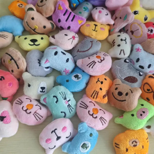 Una colección de pequeñas muñecas de peluche con forma de gatos en varios colores pastel y tierra.