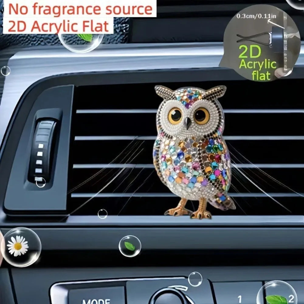 A decorative acrylic owl figurine clipped onto a car air vent.