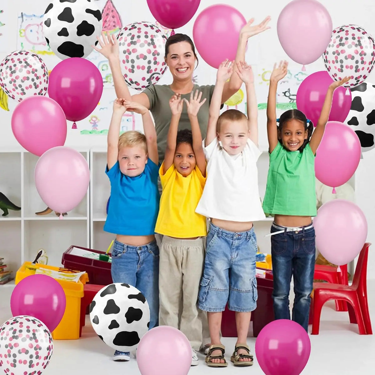 Five children are holding pink and green balloons in a farm-themed setting.