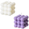 A set of two wax candles, one white and one purple, shaped like clusters of cubes.
