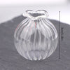 A clear glass miniature dollhouse vase and wine bottle set resting on a dark surface.
