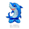 A blue shark foil balloon with a smiling face and fins, resting on a base.
