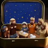 A nativity scene figurine set featuring figures like Mary Joseph and baby Jesus displayed in a gold storage box with a blue s