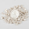 A pile of small, light beige wax sealing beads scattered on a white surface.