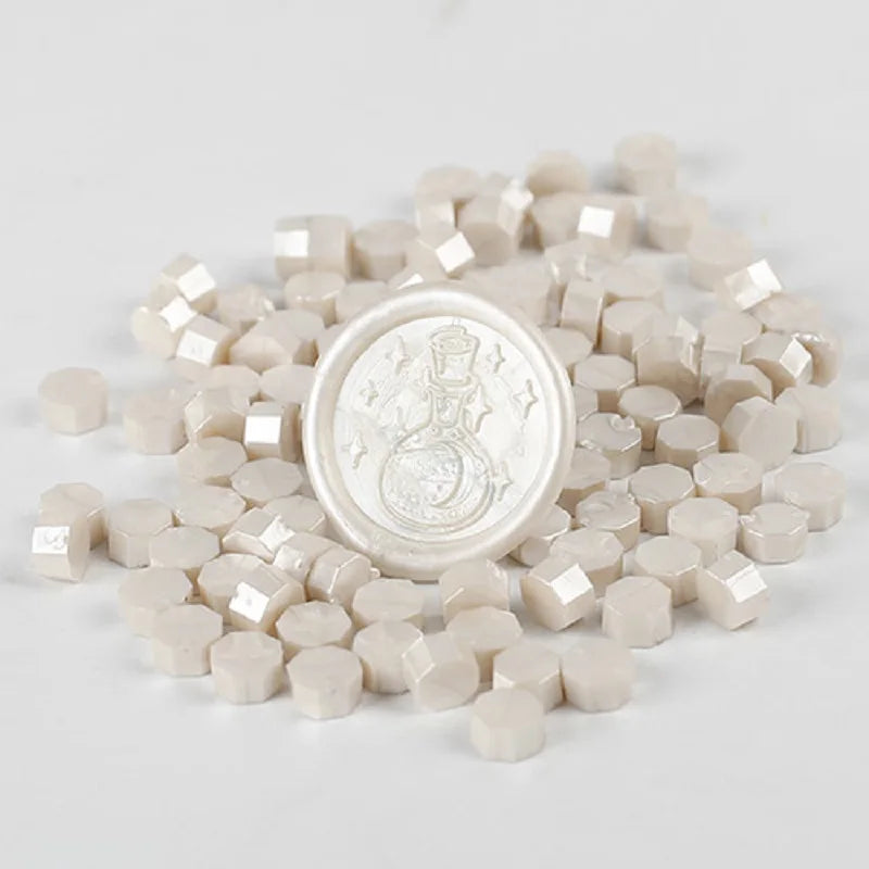 A pile of small, light beige wax sealing beads scattered on a white surface.