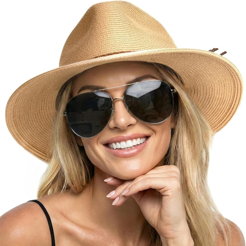 A blonde woman wearing a wide brim straw sun hat and sunglasses smiling.