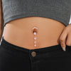 A close-up of a woman's abdomen showing a delicate gold tone butterfly and flower belly ring set.