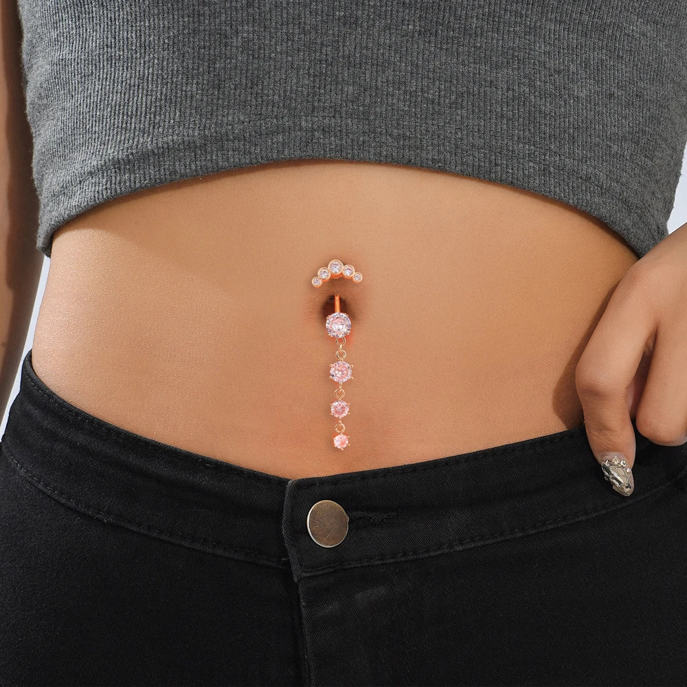 A close-up of a woman's abdomen showing a delicate gold tone butterfly and flower belly ring set.