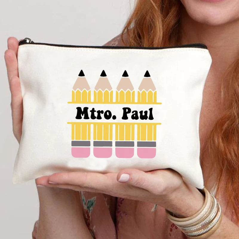 A cream-colored makeup bag featuring a graphic design of pencils in yellow, pink, and gray.