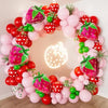 A colorful balloon arch set featuring pink, red, and green strawberries in foil and latex balloons.