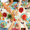 A table filled with colorful birthday party supplies including plates, fruit, and various toys for a celebration.