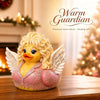A yellow resin figurine of a duck with pink wings and curly blonde hair, displayed on a wooden surface.