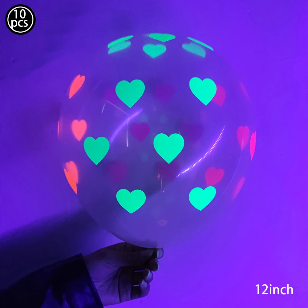 A hand holds a translucent latex balloon filled with neon glow-in-the-dark hearts against a purple background.