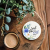 A wooden coaster features a watercolor floral design with the verse Seek Justice Love Mercy Walk Humbly from Micah 6:8