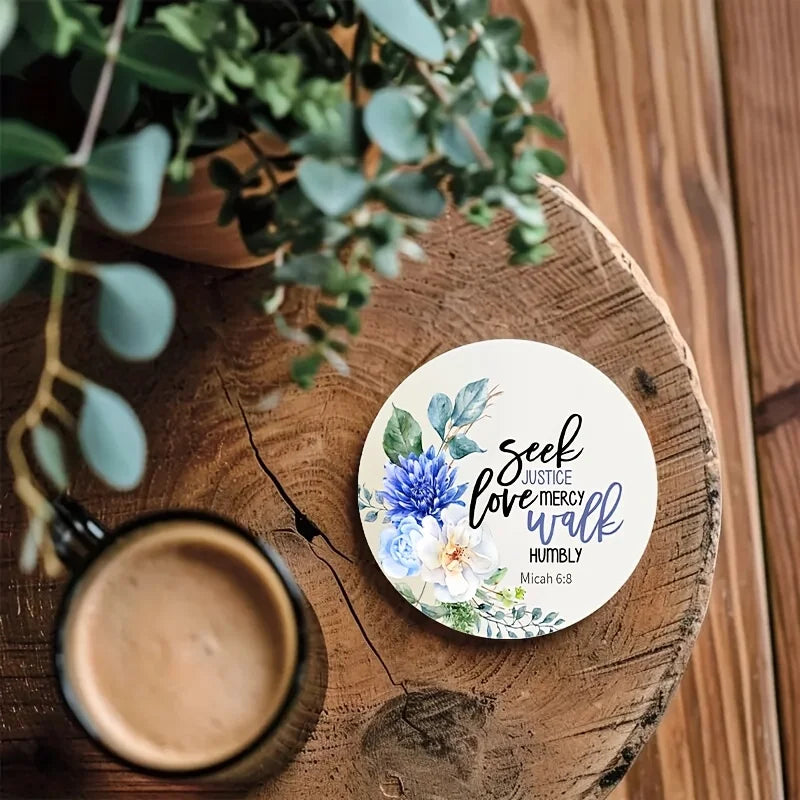 A wooden coaster features a watercolor floral design with the verse Seek Justice Love Mercy Walk Humbly from Micah 6:8