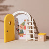 A yellow wooden door and a white ladder are displayed next to a small wooden tooth box against a neutral background.