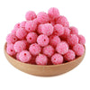 A pile of pink glittery resin beads for jewelry making in a wooden bowl.