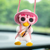 A cute pink anime duck ornament with large eyes and a yellow beak is hanging by a pink string.