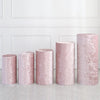 A row of four dusty rose pink spandex cylinder stand covers displayed against a white paneled wall.