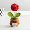 Handmade crochet sunflower desk companion with a smiling face, featuring red petals and green leaves.