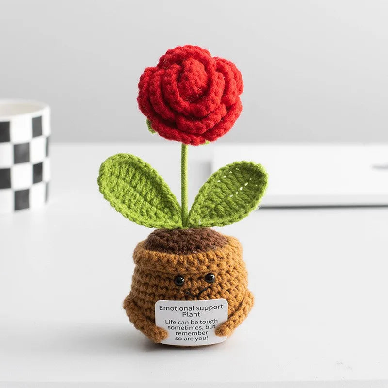 Handmade crochet sunflower desk companion with a smiling face, featuring red petals and green leaves.