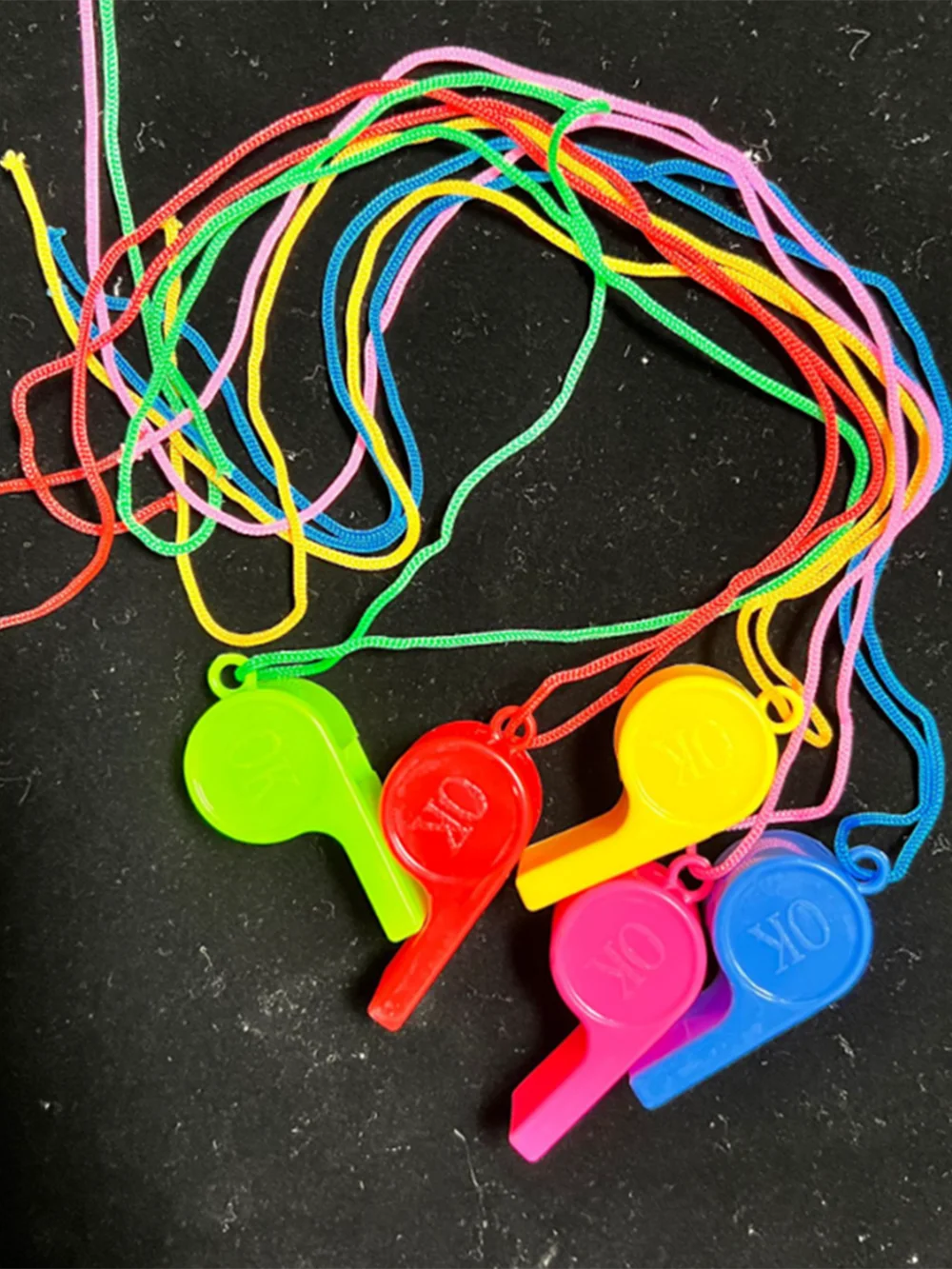 A collection of colorful plastic whistles on lanyards in various bright colors like red, green, yellow, and blue.