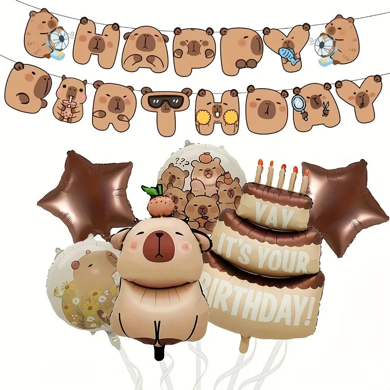 A set of capybara themed birthday decorations including foil balloons and a banner