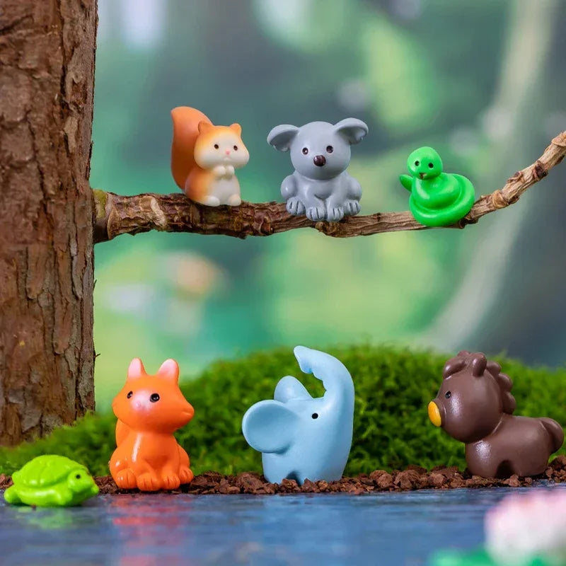 A set of mini animal fairy garden decor featuring an orange fox, a gray bear, a green frog, and a blue elephant on mossy terr
