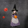 A witch ornament featuring a black pointed hat, gray hair, and purple clothing with an orange pumpkin detail, hanging against