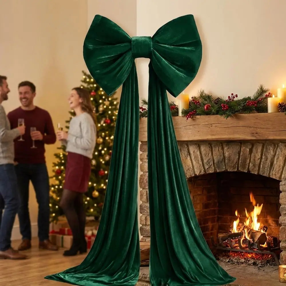 A deep emerald green velvet Christmas tree bow with long draping tails displayed on a fireplace mantel.