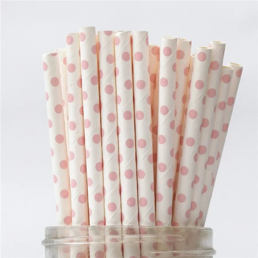 A vertical arrangement of white drinking straws with pink polka dots on a clear stand.