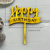 Gold acrylic birthday cake topper with the words Happy Birthday on a wooden stick