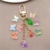 Joyería de color dorado con cierre y cadena, con diversas cuentas de mariposa de vidrio coloridas.