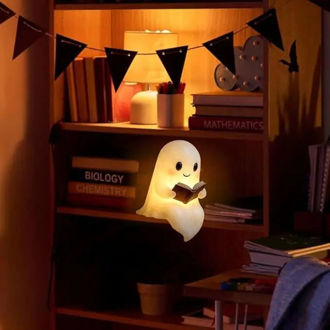 A cute ghost figurine lamp with a warm glow illuminates a shelf filled with books and decorative elements.