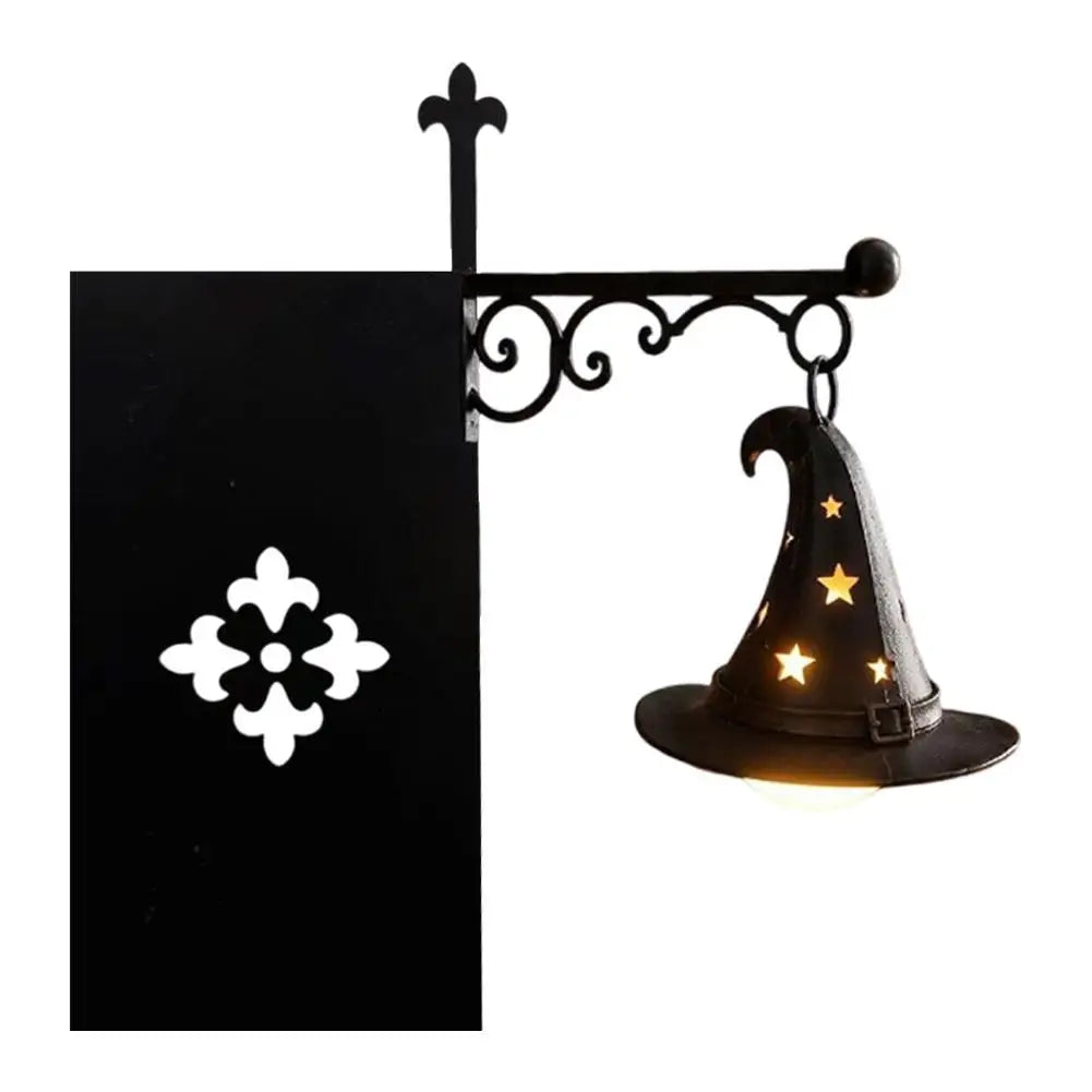 A black metal book nook lamp shaped like a witch's hat with a warm glow.