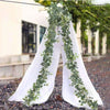 White fabric draped with a long garland of green eucalyptus leaves and white flowers for wedding decor
